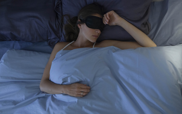 ベッドでアイマスクをして、目を隠して眠る女性