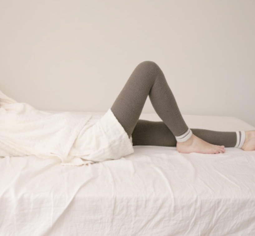 部屋のベッドで、レギンスを履いて眠る女性