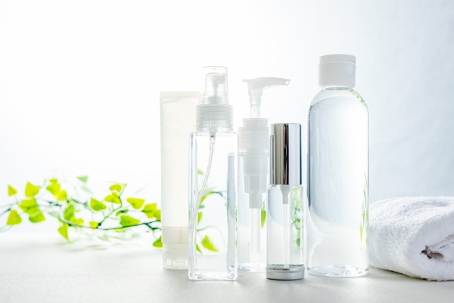 緑の観葉植物とともに並べられた化粧水などが入った数種類の容器