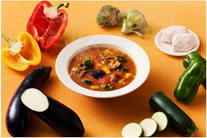 お皿に注がれた野菜スープと、その周りを取り囲む数種類の野菜