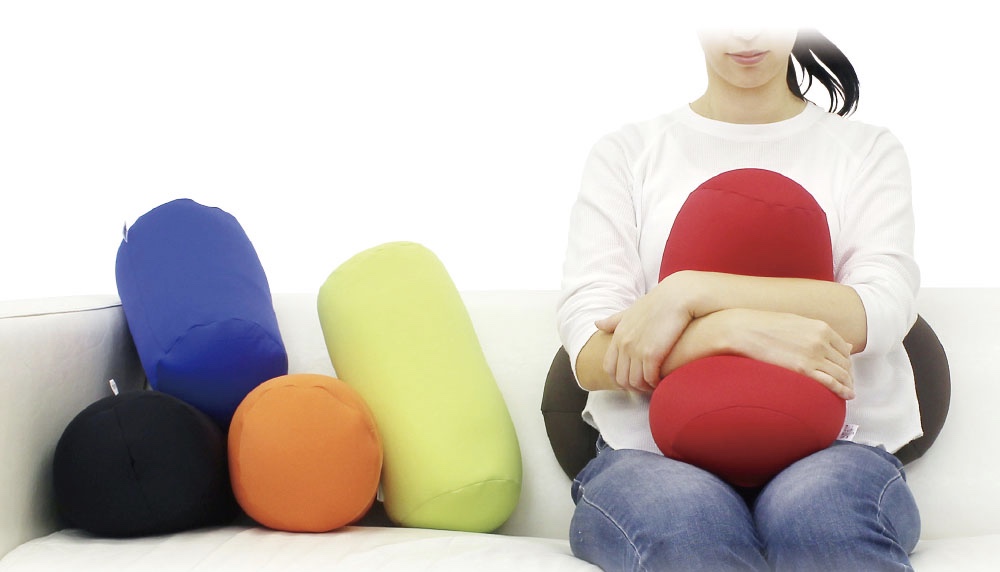 ビーズマクラを抱っこしながら、ソファに腰かける女性と、さまざまなカラー展開のビーズ枕