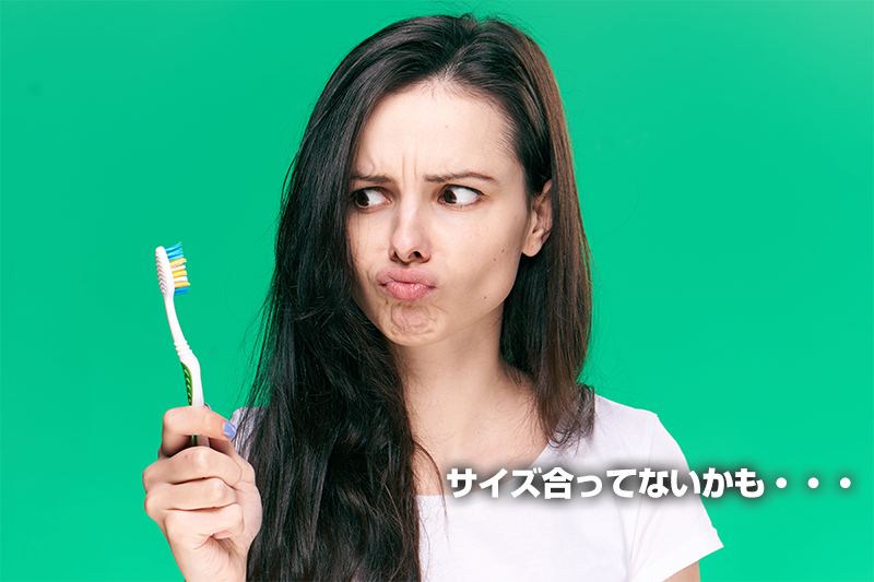 歯ブラシを手に持ち、ブラシのサイズが口に合っていないことに困る女性